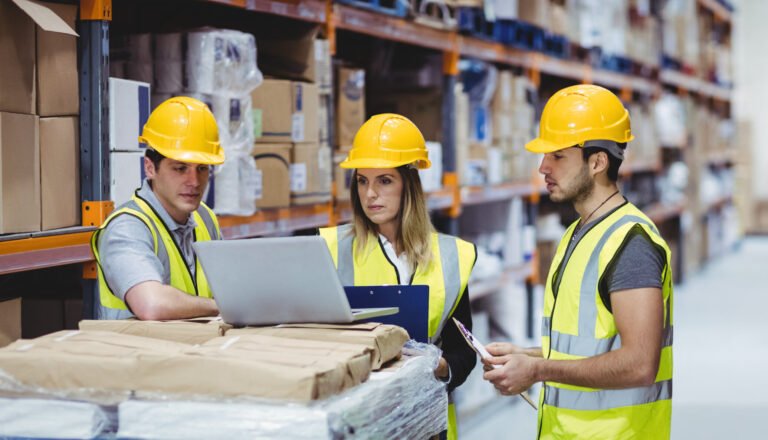 Portrait of smiling warehouse managers using laptop