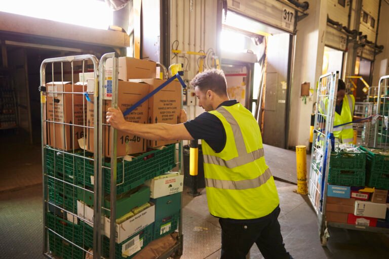 Man pushing a roll cage ready for delivery in a warehouse